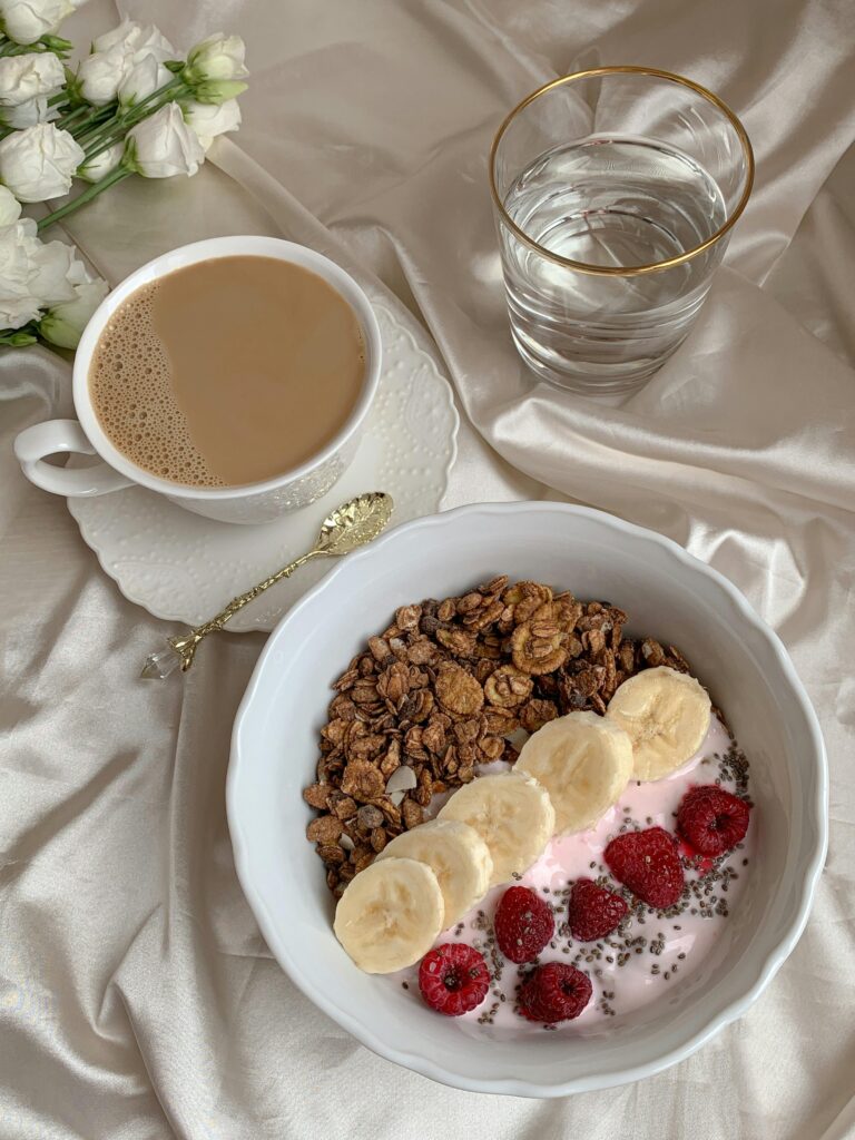 Delicious breakfast with banana, raspberry yogurt, and coffee on elegant table setting.